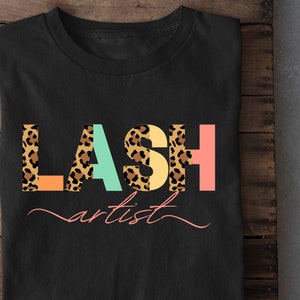 May include: Black t-shirt with the text "LASH artist" in colorful letters with a leopard print pattern.