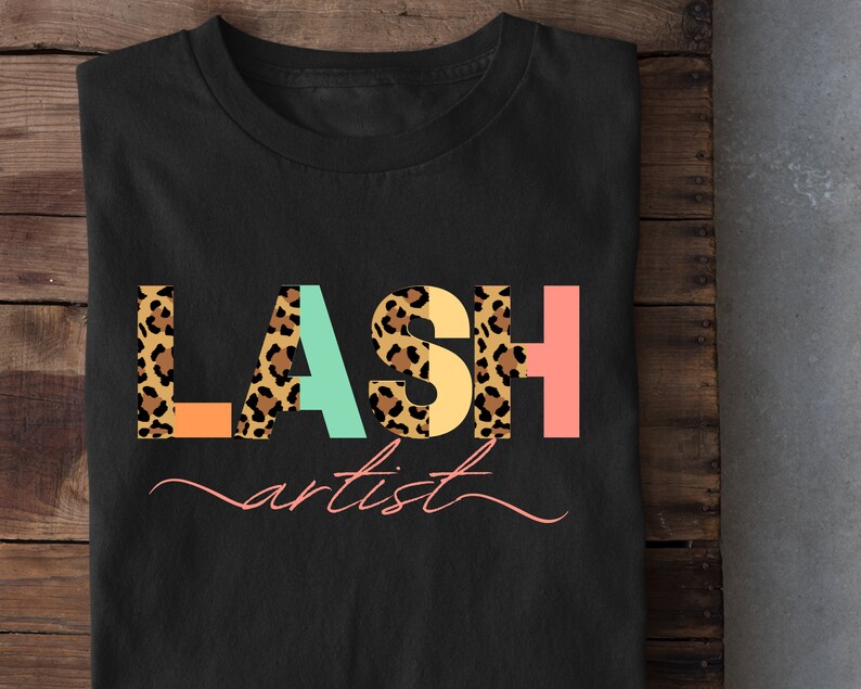 May include: Black t-shirt with the text "LASH artist" in colorful letters with a leopard print pattern.
