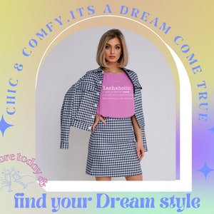 May include: A woman wearing a pink t-shirt with the text "Lashaholic: (Last-a-holic) A person who is addicted to eyelashes. Excessive lashing. No plans for recovery." and a black and white checked skirt. The text "CHIC & COMFY, ITS A DREAM COME TRUE" is in a circle around her. The text "Shop our store today & find your Dream style" is at the bottom of the image.
