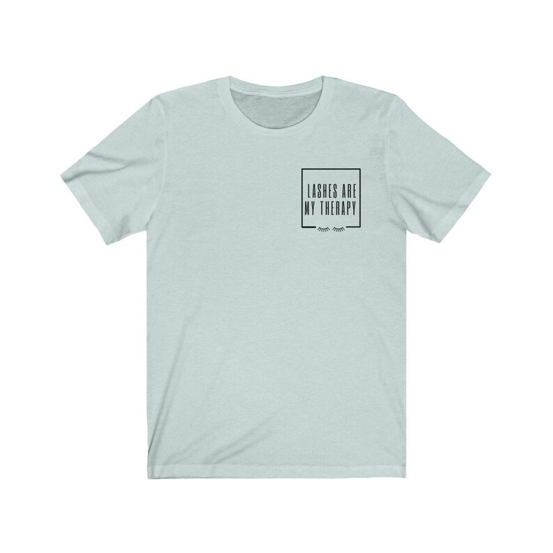 May include: A light blue t-shirt with the text "Lashes are my therapy" in a black box with eyelashes underneath.