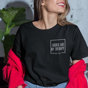 May include: A black t-shirt with the text "Lashes are my therapy" in a white box with a pair of eyelashes below the text.