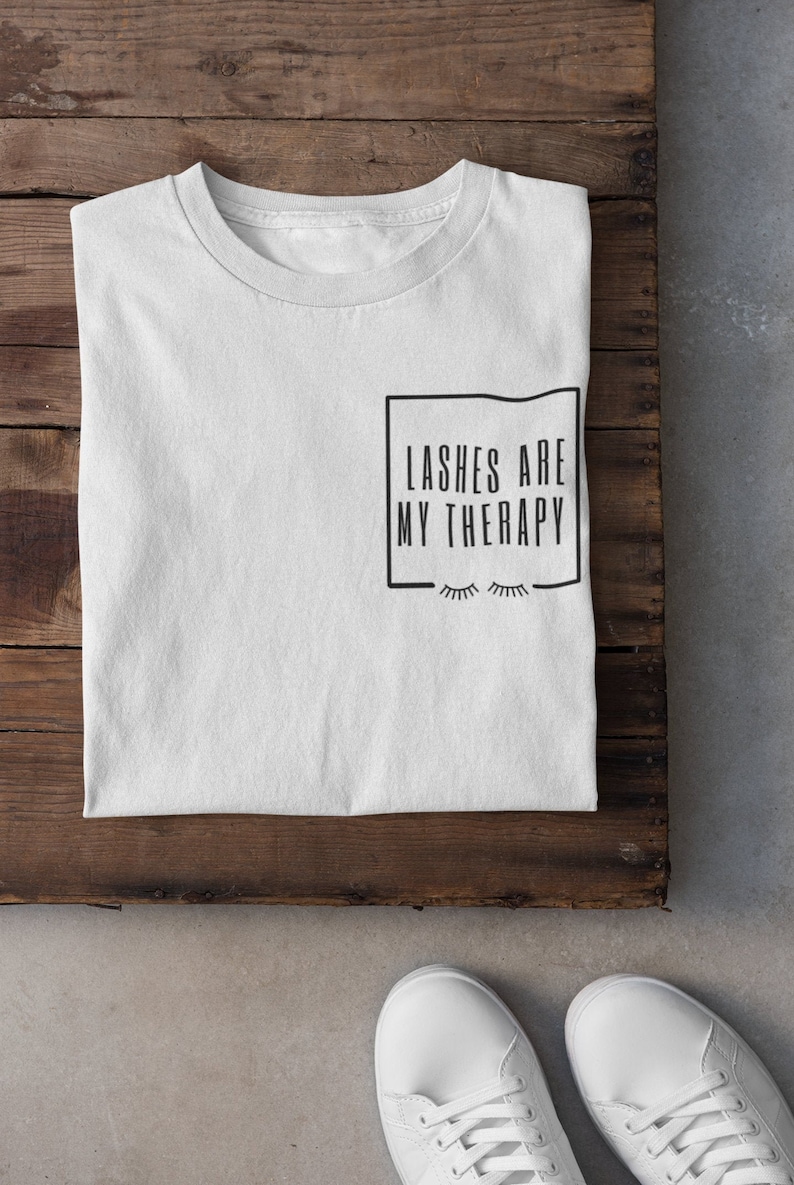 May include: White t-shirt with black text that reads "Lashes are my therapy" inside a black square.  Eyelashes are drawn below the text.