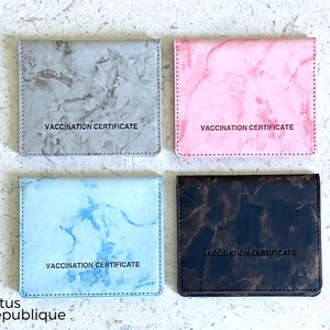 May include: Four different colored card holders with a marble pattern. Each card holder has the text "Vaccination Certificate" printed on the front.
