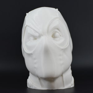 May include: White 3D printed bust of a masked superhero head. The mask has a detailed design with a prominent nose and eye holes.