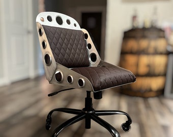 May include: A brown leather office chair with a metal frame and a swivel base. The chair has a unique design with multiple holes in the back and seat.