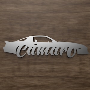 以下が含まれることがあります： 車のシルエットが銀色の金属でできており、下に「Camaro」という文字がスタイリッシュなフォントで書かれています。