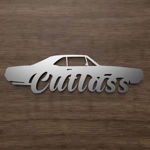 May include: A silver metal cutout of a classic car with the word "Cutlass" written in a stylized font below it.