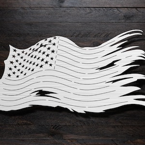 May include: A white distressed American flag with red and white stripes and blue stars. The flag is waving in the wind and has a tattered look.