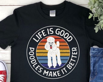 May include: Black t-shirt with a white graphic of a poodle and the text "LIFE IS GOOD, POODLES MAKE IT BETTER" in a circular design. The poodle is white with a pink tongue. The background has horizontal stripes of orange, yellow, blue, and green.