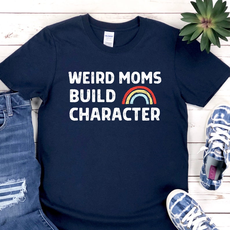May include: A navy blue t-shirt with white text that reads "Weird Moms Build Character" and a rainbow graphic.