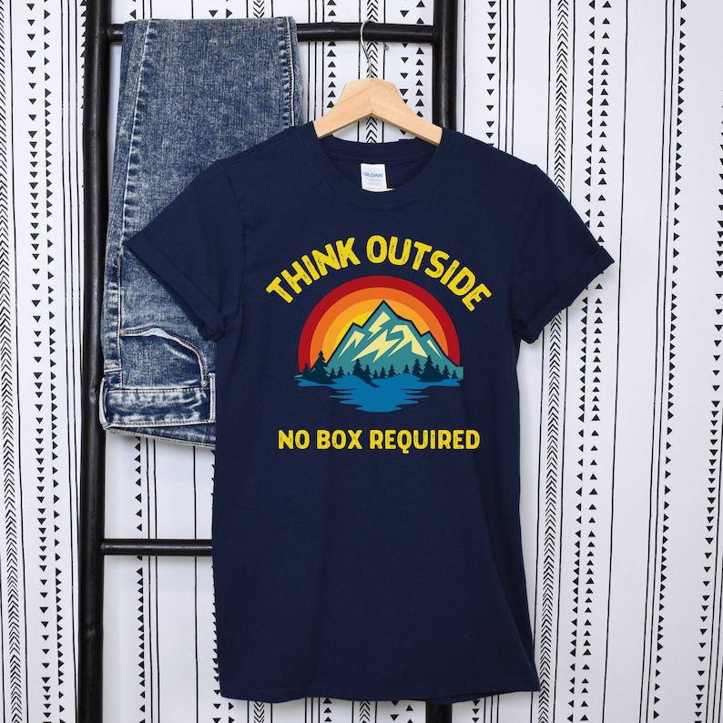 May include: Navy blue t-shirt with a retro mountain scene and the text "Think Outside No Box Required".