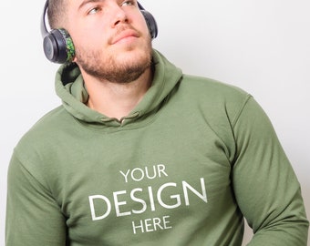 May include: An olive green hooded sweatshirt featuring a front kangaroo pocket and the white text "YOUR DESIGN HERE" printed on the chest. The hoodie includes a matching drawstring at the neckline and long sleeves with ribbed cuffs.