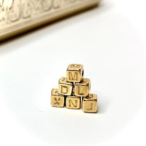 Può includere: Un mucchio di perline di lettere dorate che compongono la parola "XMLJ".