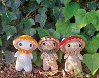 May include: Three crocheted mushroom plushies with different colored hats. The mushroom on the left has a yellow hat, the middle mushroom has a brown hat, and the mushroom on the right has a red hat.