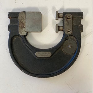 Puede incluir: Un calibre interior de metal negro con una cara de medición plateada y una etiqueta plateada que dice "PHOENIX GAGE CO. PHOENIX, N.Y."