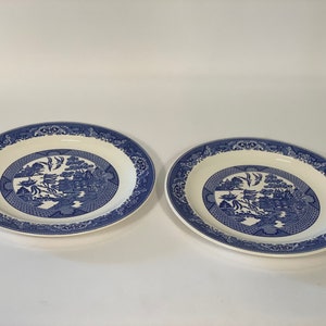 Puede incluir: Dos fuentes ovaladas con un patrón Willow azul y blanco. Las fuentes tienen un borde azul y un diseño central con una escena de paisaje. Los platos son de cerámica.