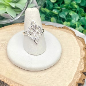May include: A silver ring with a Celtic knot design and clear cubic zirconia stones.