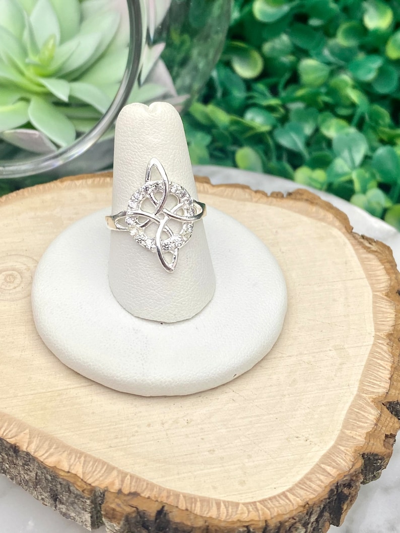 May include: A silver ring with a Celtic knot design and clear cubic zirconia stones.