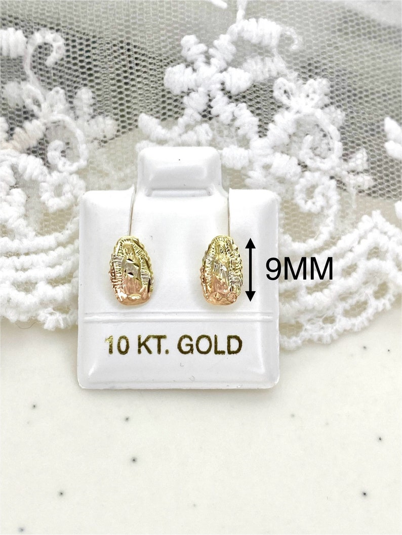 Op de afbeelding: Goudkleurige oorstekers met een gedetailleerd ontwerp, gepresenteerd op een witte standaard. De oorbellen zijn ongeveer 9 mm groot. De standaard is gemarkeerd met '10 KT. GOLD'.