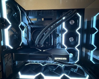 May include: A black computer case with a clear glass side panel. The case has white LED lights around the fans and the graphics card. The graphics card has the text "GEFORCE RTX" on it.