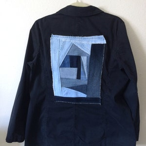 May include: A black blazer with a large patchwork design on the back. The patchwork is made of different shades of blue denim.
