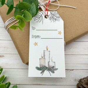 May include: White gift tag with a drawing of three candles and pine branches. The tag has the words "To:" and "From:" with blank lines for writing.