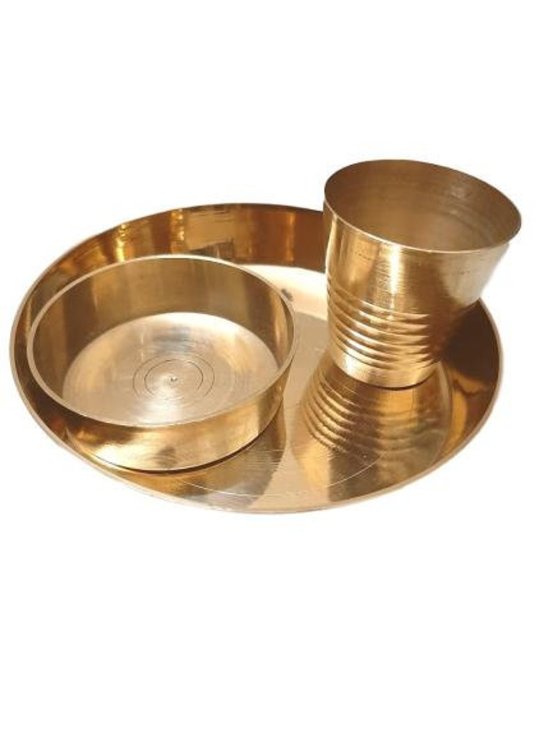 May include: A set of three gold-coloured metal bowls. The largest bowl is a plate with a slightly raised rim. The middle bowl is a smaller bowl with a slightly raised rim. The smallest bowl is a cup with a rounded bottom and a slightly flared rim.