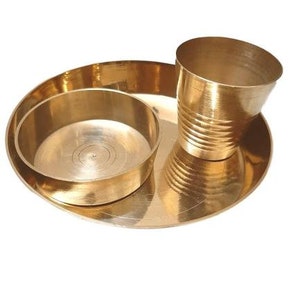 May include: A set of three gold-coloured metal bowls. The largest bowl is a plate with a slightly raised rim. The middle bowl is a smaller bowl with a slightly raised rim. The smallest bowl is a cup with a rounded bottom and a slightly flared rim.
