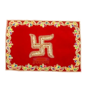 Puede incluir: Un cuadrado decorativo de terciopelo rojo con un símbolo de esvástica bordado en oro en el centro. El borde está decorado con hojas bordadas de colores y el texto "परमन्तव" está impreso en oro debajo de la esvástica.