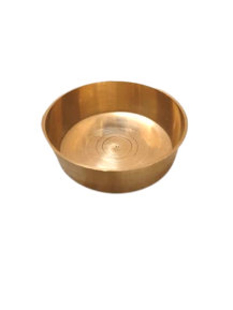 May include: A small, round, brass bowl with a smooth, shiny surface. The bowl has a slightly raised lip around the edge.