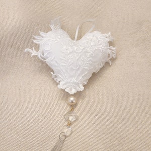 Könnte beinhalten: Weißer Herz-Anhänger aus Spitze mit einer Perle und einem Kristalltropfen.