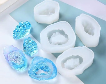 May include: Set of six silicone molds for making resin crafts. The molds are shaped like agate slices with a clear center and a white outer edge. There are also three small blue resin pieces that look like agate.