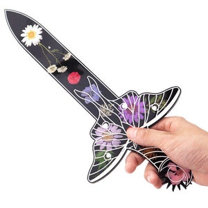 Könnte beinhalten: Ein schwarzes, schwertartiges Dekorationsobjekt mit einem Schmetterlings- und Blumendesign. Das Objekt besteht aus schwarzem Kunststoff und hat ein detailliertes Design aus gepressten Blumen und einem Schmetterling.