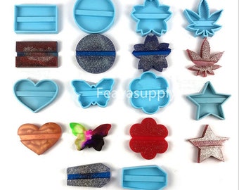 May include: A set of 12 silicone molds for resin crafts. The molds are in various shapes, including hearts, stars, butterflies, flowers, and leaves. The molds are blue and have a smooth finish. Some of the molds have a glitter finish.