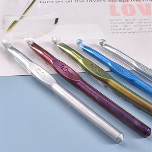 May include: Five crochet hooks of different sizes and colors. The hooks are made of metal and have a shiny finish. The hooks are labeled with their sizes in millimeters: 10.0mm, 9.0mm, 8.0mm, 6.0mm, and 5.0mm.