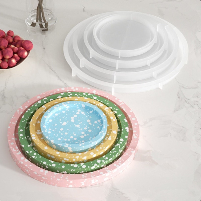 May include: Set of four nesting trays with speckled paint. The trays are pink, green, yellow, and light blue. The trays are stacked on top of each other.