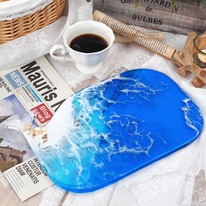 May include: A blue and white resin serving tray with a wave design. The tray is oval shaped and has a glossy finish.
