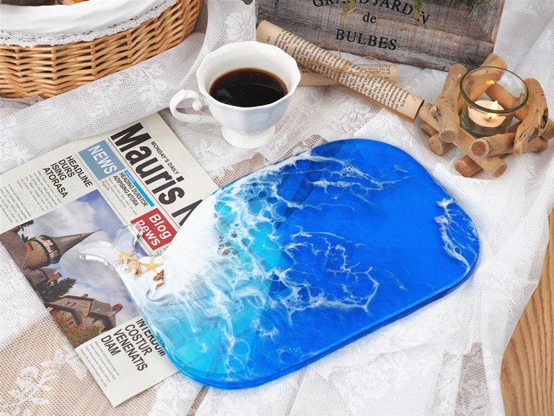 May include: A blue and white resin serving tray with a wave design. The tray is oval shaped and has a glossy finish.
