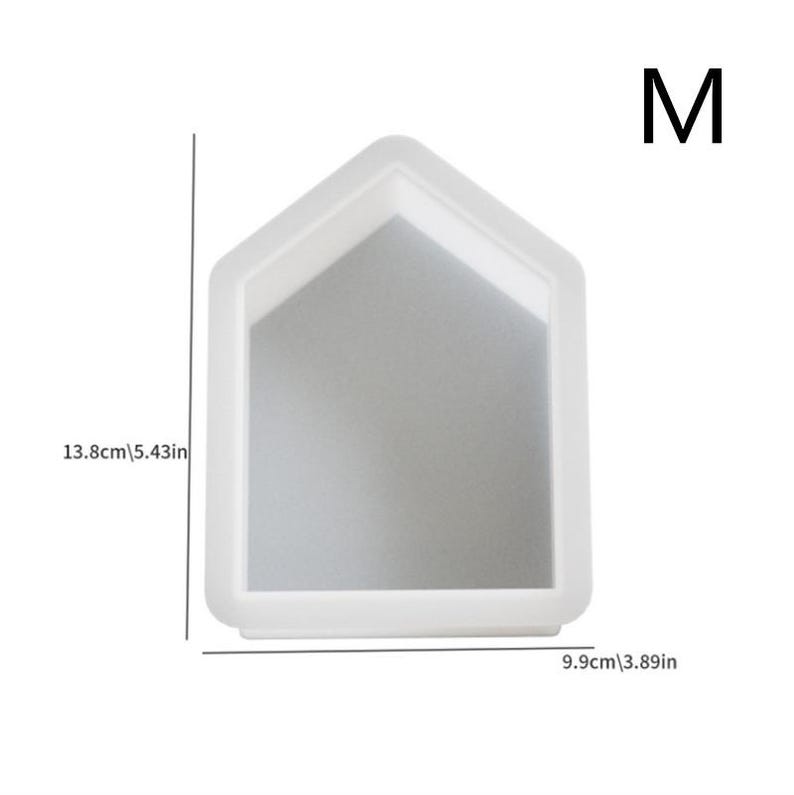 Op de afbeelding: Witte siliconen mal in de vorm van een huis met de letter "M" in de rechterbovenhoek. De mal is 13,8 cm hoog en 9,9 cm breed.