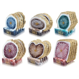 May include: Set of six agate coasters with gold trim. Each coaster features a different color and pattern, including blue, green, brown, pink, and white. The coasters are stacked on top of each other and have a gold stand. The text "You are my reason to smile" is printed on the stand.