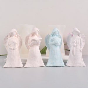 May include: Four white angel figurines with wings. One angel is holding a book, one is holding a heart, one is holding a bouquet of flowers, and one is holding a house. The angels are painted in different colours: pink, white, blue, and white.