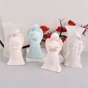 May include: Four white angel figurines, each with a different pose and holding a different object. One angel is holding a book, another is holding a heart, another is holding a flower, and the last one is holding a clock. The angels are all standing on a white surface.