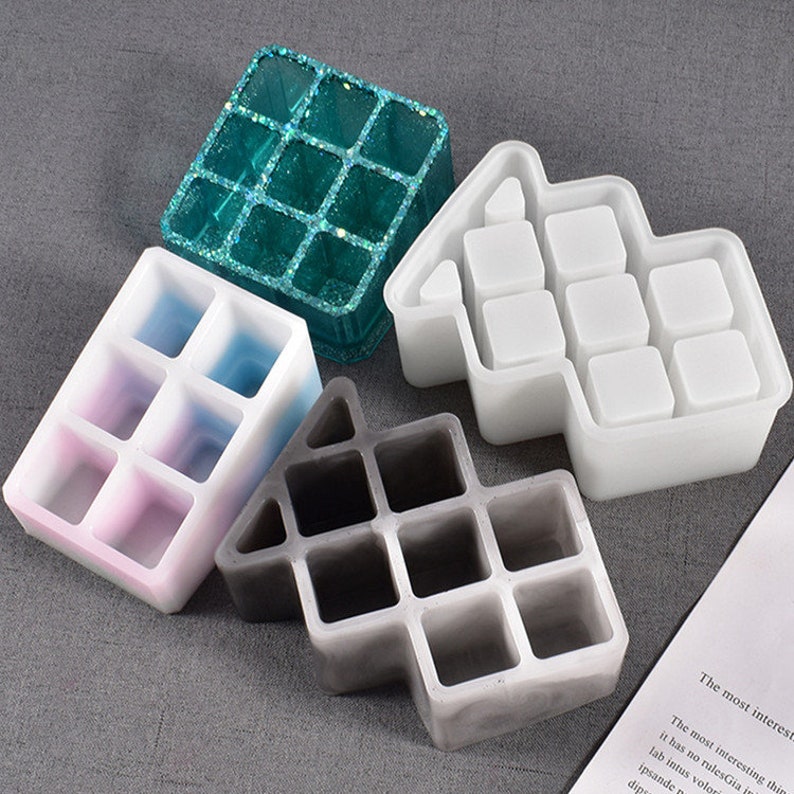 May include: Four silicone molds for making resin crafts. The molds are shaped like houses with multiple square compartments. The molds are in different colors: teal, white, pink and gray.