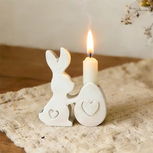 Może przedstawiać: Zestaw trzech ceramicznych kubków z nakrapianym, matowym wykończeniem. Kubki są w odcieniach kremu, jasnoszarym i ciemnoszarym. Każdy kubek ma prosty, minimalistyczny design i zaokrąglony uchwyt.