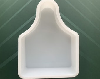 May include: White silicone mould shaped like a cow tag. The mould has a smooth, glossy finish and a rounded top.