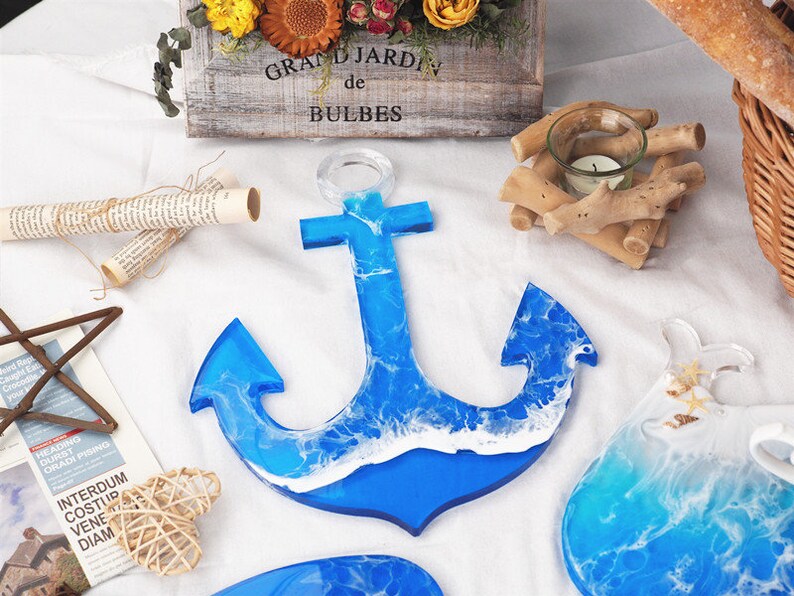May include: A blue resin anchor with white waves, a popular nautical decor item. The anchor is a decorative piece with a resin finish.