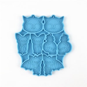 Puede incluir: Molde de silicona azul con ocho formas diferentes de tem&aacute;tica de Halloween: dos murci&eacute;lagos, dos calaveras con flores, dos calaveras con puntadas y dos murci&eacute;lagos con las alas extendidas.
