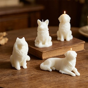 Puede incluir: Cuatro velas blancas con forma de perro con mechas encendidas están dispuestas sobre una superficie de madera. Las velas representan diferentes razas de perros en varias poses, incluyendo sentados y tumbados. Las velas son sin perfume y decorativas.