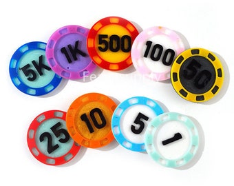 Puede incluir: Un conjunto de nueve fichas de póquer de plástico de colores con números negros. Las fichas están en denominaciones de 1, 5, 10, 25, 50, 100, 500, 1K y 5K.