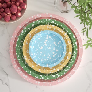 May include: Set of four nesting plates with a speckled design. The plates are pink, green, yellow, and blue with white speckles.